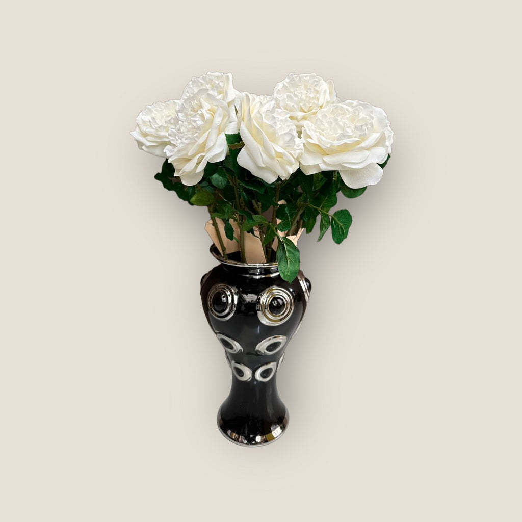 Een prachtige zwarte vaas met 10 grote, witte bloemen.